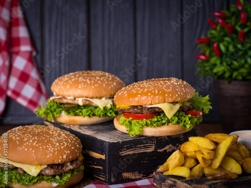 juicy burgers with a red napkin and fries on a black wooden background