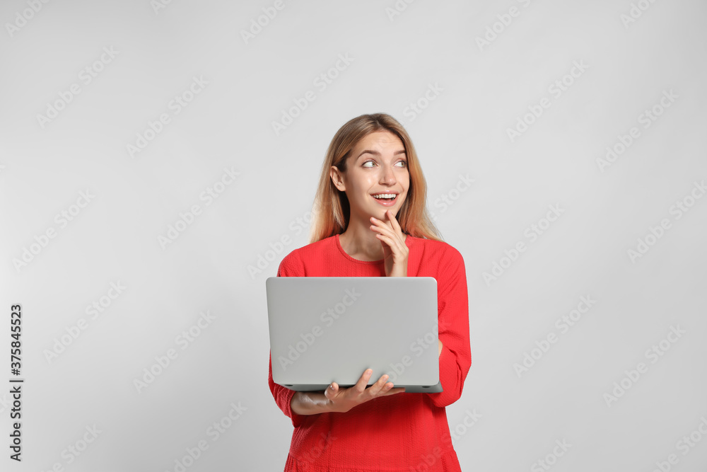 Portrait of emotional woman with modern laptop on light grey background Portrait of emotional woman with modern laptop on light grey background