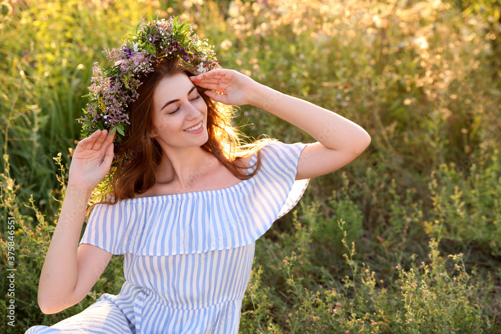 Young woman wearing wreath made of beautiful flowers outdoors on sunny day Young woman wearing wreath made of beautiful flowers outdoors on sunny day