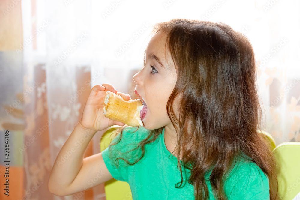 Portrait of a little beautiful girl eating ice cream in a children's room
