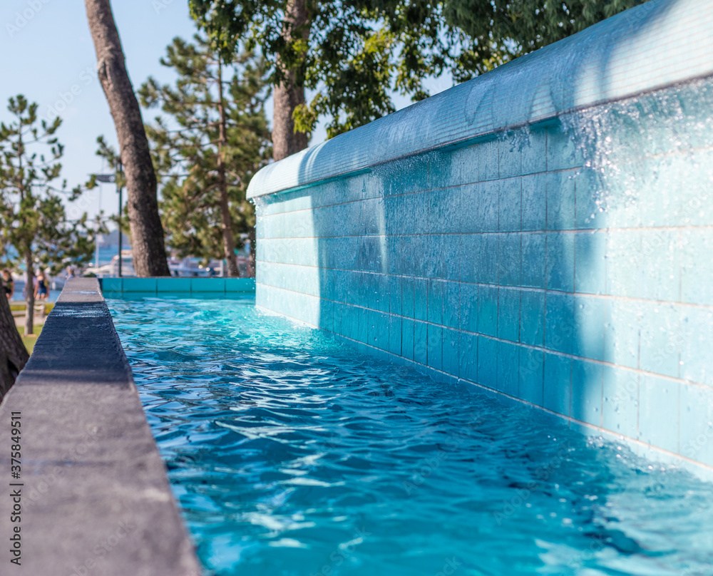 Obraz premium Water in a pool overflowing from the upper one to the bottom one. Crystal clear blue water in an outside pool in croatia