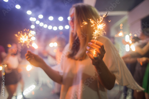 Beautiful blonde woman holding sparklers at the party