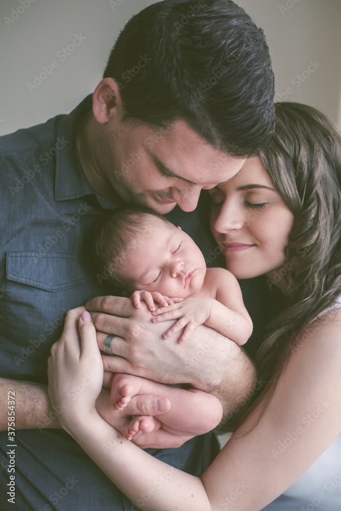 New family together. Mother and father hugging and snuggling with their newborn baby. New family together. Mother and father hugging and snuggling with their newborn baby.