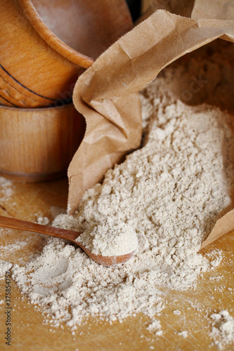 Hazelnut flour in a wooden spoon on a wooden table.