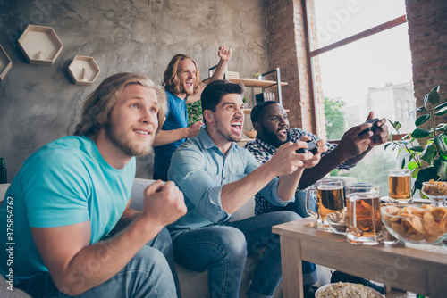 Portrait of four nice attractive cheerful cheery crazy addicted guys playing video game sport cup championship having fun at industrial loft style interior house apartment flat indoors