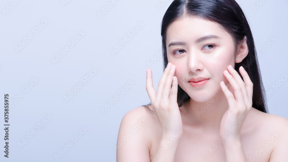 Beauty skin care young asian woman smile to you isolated on blue background. Beautiful model applying cosmetic cream treatment on her face. Beauty skin care young asian woman smile to you isolated on blue background. Beautiful model applying cosmetic cream treatment on her face.