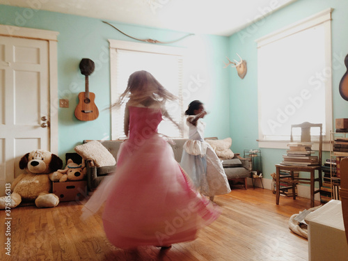 two girls spinning in house with fancy dresses