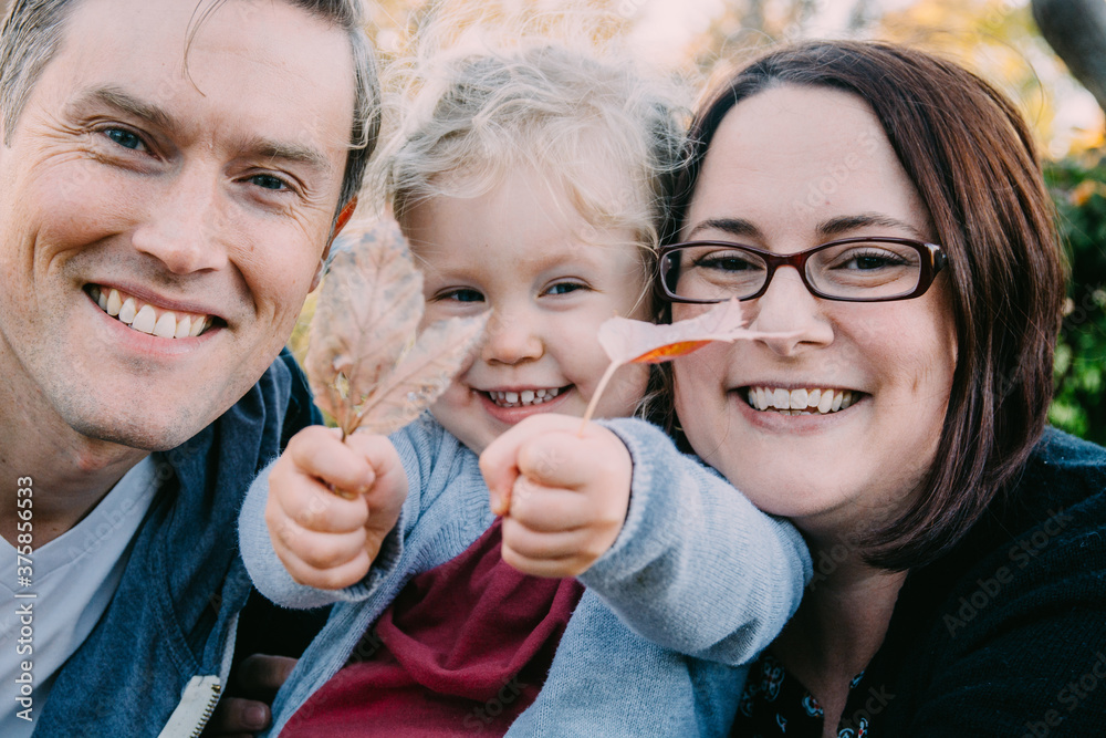 Happy family with their girl holding autumn leaves Happy family with their girl holding autumn leaves