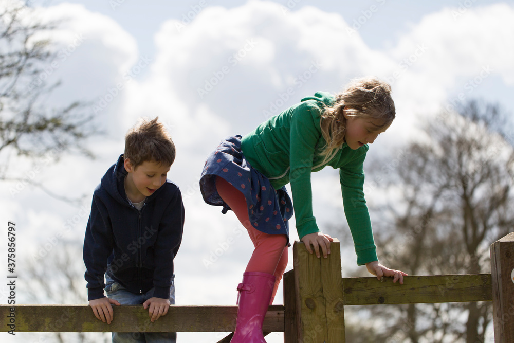 Children climb a fence in the countryside Children climb a fence in the countryside