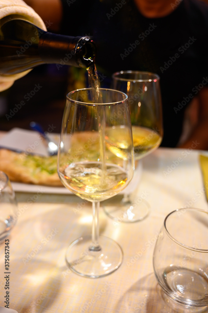 Pouring in glass cold dry white wine in outdoor cafe at night in Italy Pouring in glass cold dry white wine in outdoor cafe at night in Italy