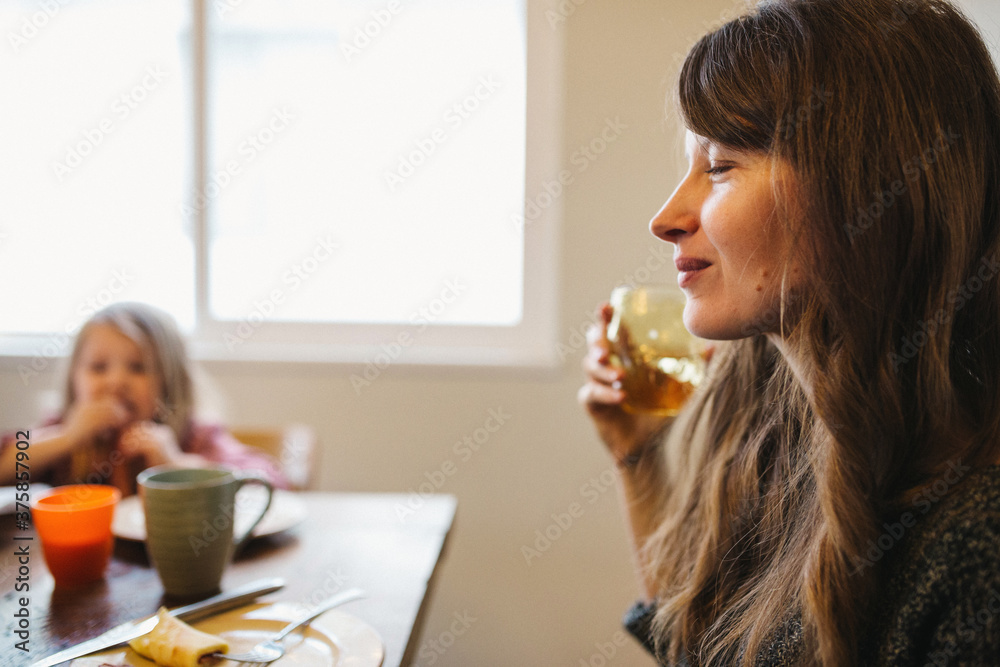 Young content mother relaxing at breakfast table Young content mother relaxing at breakfast table