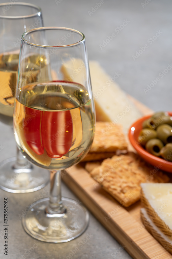 Glasses of dry fino sherry wine served with spanish tapas, manchego cheese, green olives, cheese crackers