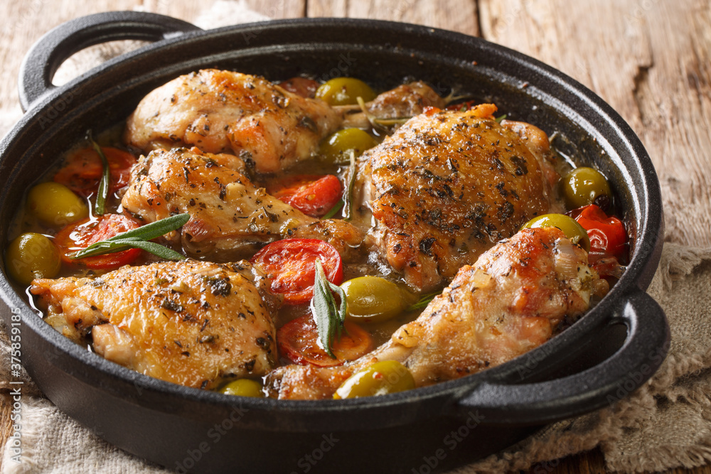 Rustic style chicken baked with green olives, tomatoes and onions, herbs close-up in a pan on the table. horizontal