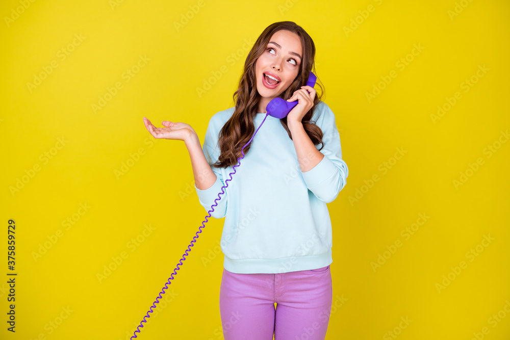 Photo of cute lovely girl hold phone order pizza delivery pretending stupid dreamy look up empty space wear blue sweater violet trousers isolated vivid yellow color background Photo of cute lovely girl hold phone order pizza delivery pretending stupid dreamy look up empty space wear blue sweater violet trousers isolated vivid yellow color background