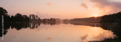 Swans on a misty lake at sunrise. Lynford Lakes, Norfolk, UK. photo