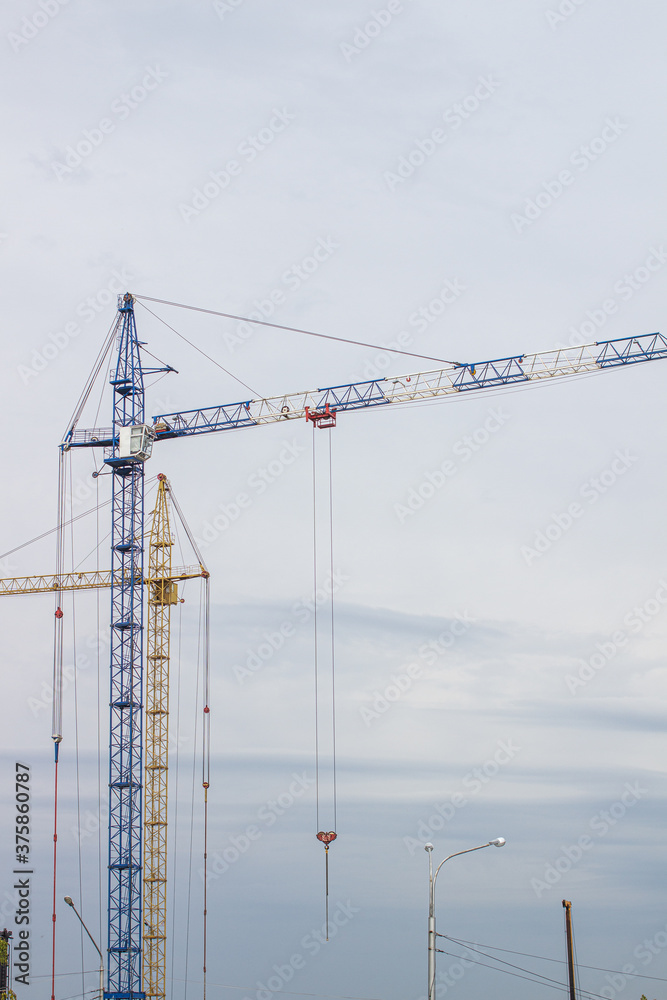 Construction site with high cranes against the blue sky Construction site with high cranes against the blue sky