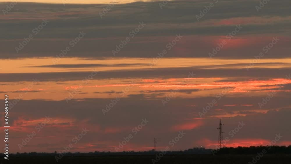 Time lapse on a lovely evening of the sky and clouds burning with color while a beautiful sunset is happening in the distance Time lapse on a lovely evening of the sky and clouds burning with color while a beautiful sunset is happening in the distance