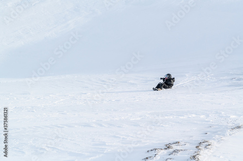 A woman slipping down the hillside on Svalbard, Spitsbergen. Winter fun.