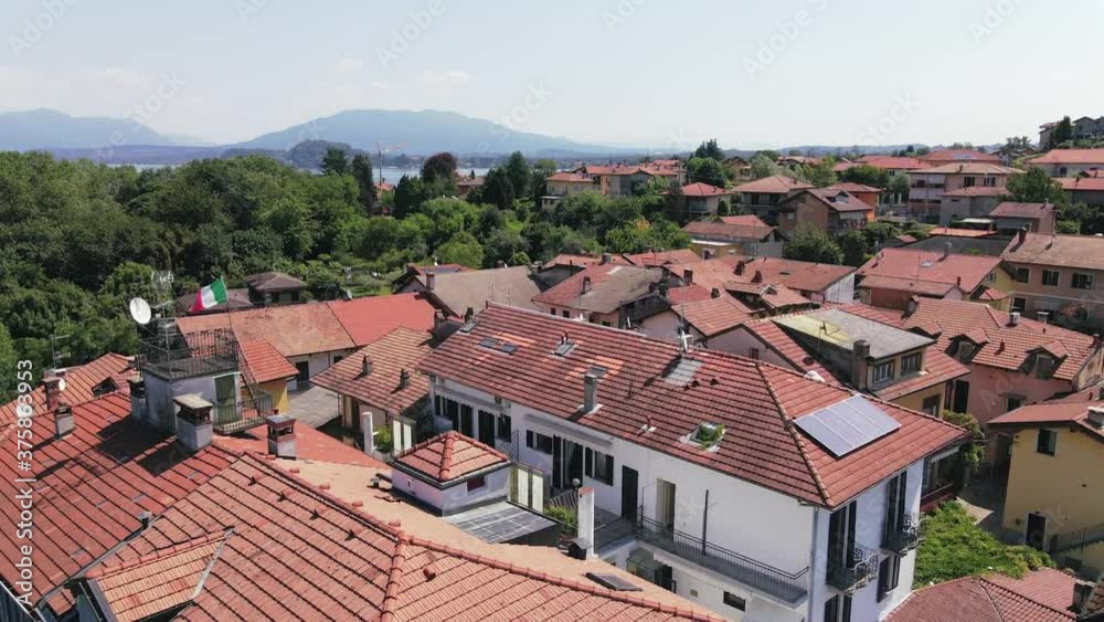 Scenic backward flyover above Il sole di Ranco restaurant, resort, and red terracotta village roofs with scenic view of Lake Maggiore mountain range in background, Italy, overhead aerial pull back Scenic backward flyover above Il sole di Ranco restaurant, resort, and red terracotta village roofs with scenic view of Lake Maggiore mountain range in background, Italy, overhead aerial pull back