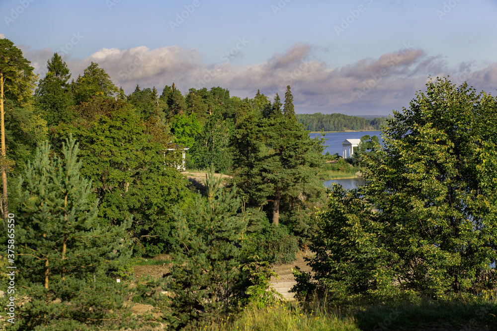 Landscape with a steep granite coast and a bay of the Baltic sea. With a white gazebo in the distance