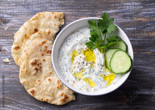Принти на полотні Traditional greek yogurt tzatziki sauce with cucumbers and herbs on wooden backg