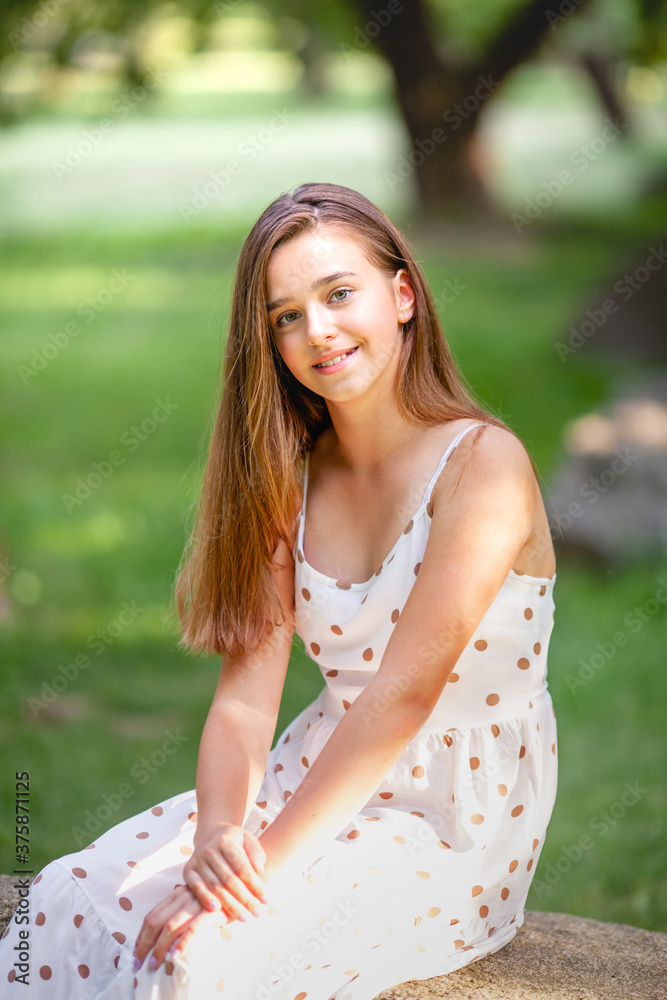 beautiful long-haired girl in a summer dress sits on a stone beautiful long-haired girl in a summer dress sits on a stone