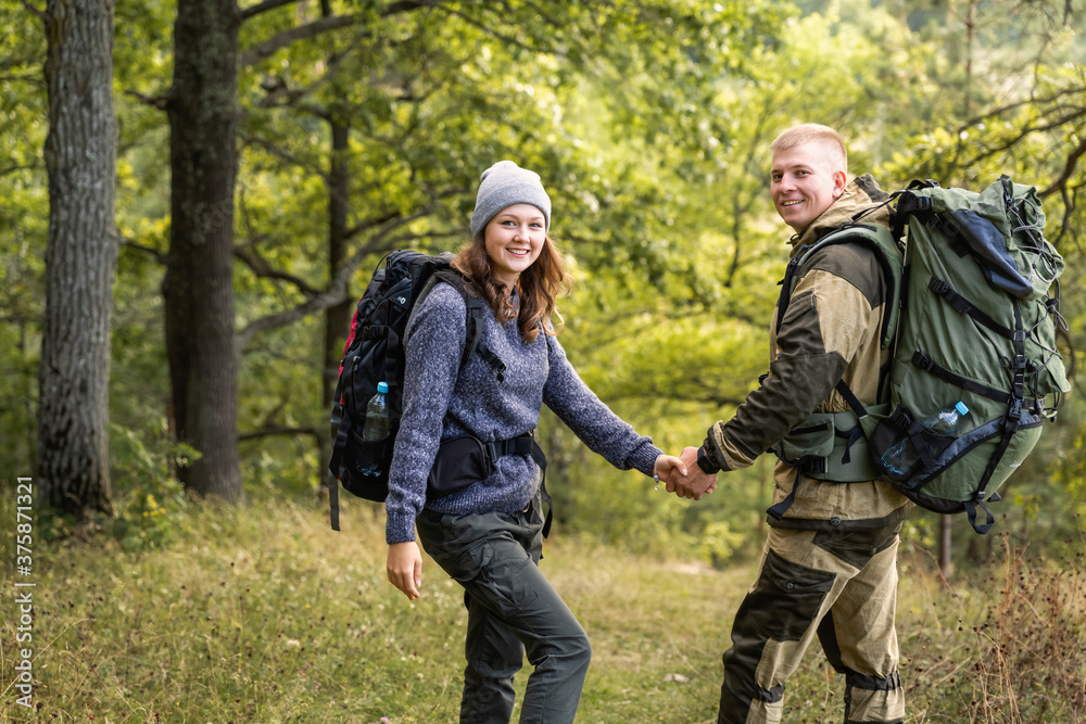 A young girl and her boyfriend are walking in the forest, enjoying nature.