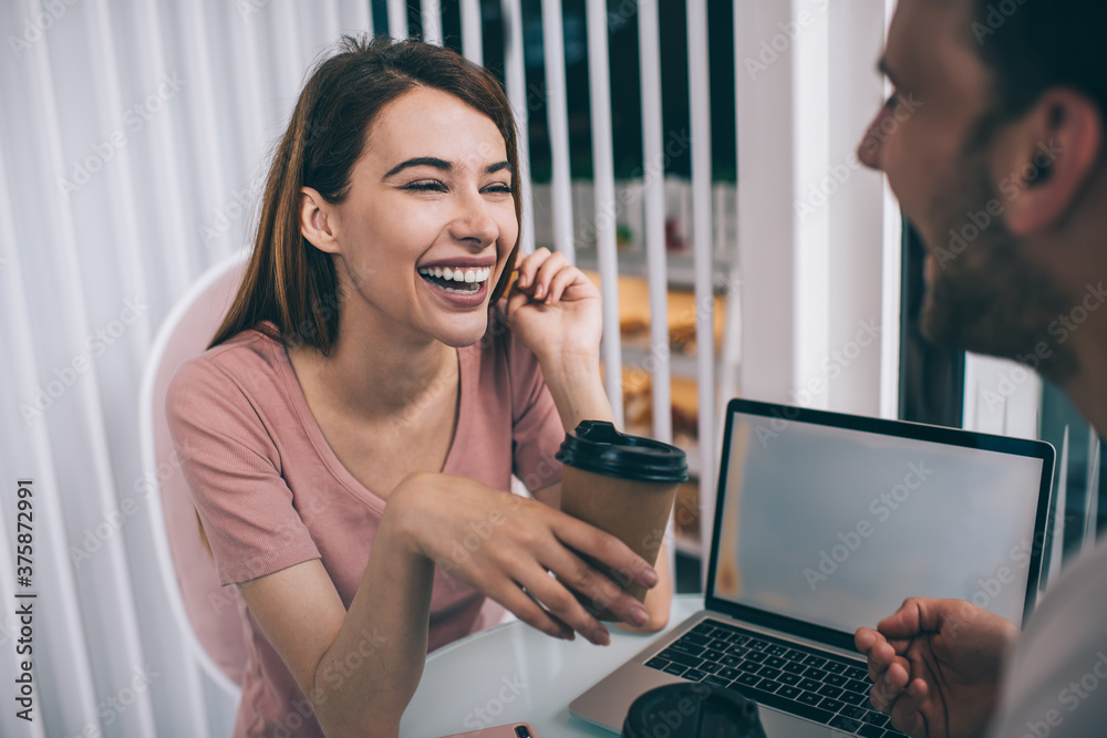 Woman laughing while chatting with guy in office Woman laughing while chatting with guy in office