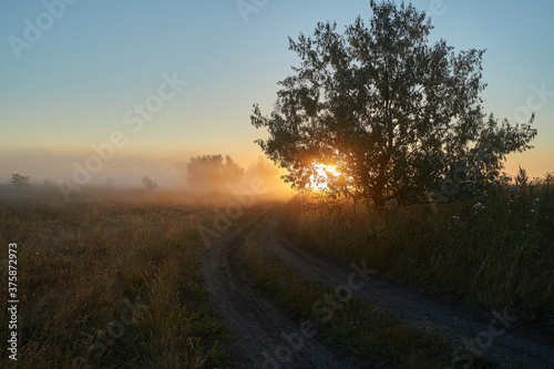 Autumn time. Dawn over the river in a misty, brooding haze. Beautiful view of the forest and river, covered with fog in the early morning. The sun's rays of light. September.