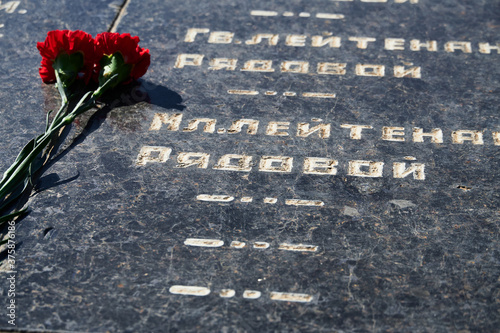 flowers on the memorial to fallen soldiers, red carnations on black marble, Russian text of soldiers military rank - sergeant,major, colonel,Lieutenant Colonel, private, corporal