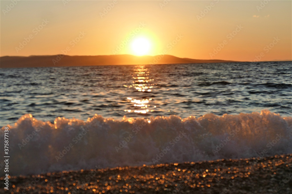 Obraz premium Beautiful orange sunset with waves on th beach