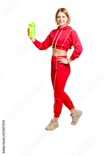 A young fitness woman in a red workout dress. He holds a green shaker in his hand.