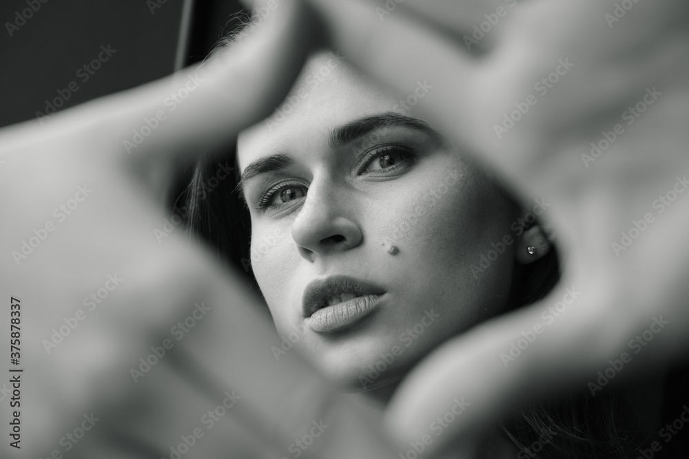 Beautiful woman making a hand frame over gray background. Black and white Beautiful woman making a hand frame over gray background. Black and white