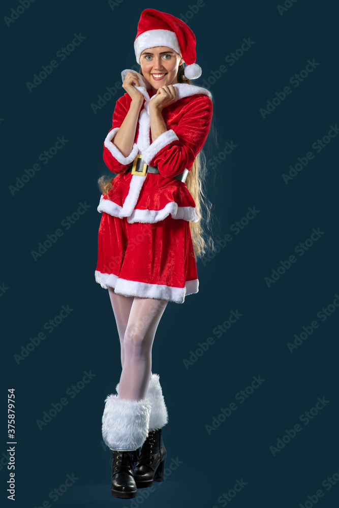 Nikolaus Lady in rotem Nikolaus Kostüm , Studioaufnahme vor blauem  Hintergrund, freut sich auf Weihnachten. Photos | Adobe Stock