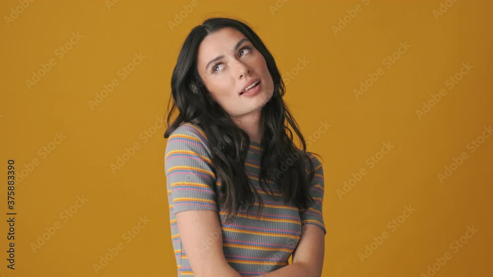 A good-looking young woman is posing standing isolated over yellow background A good-looking young woman is posing standing isolated over yellow background