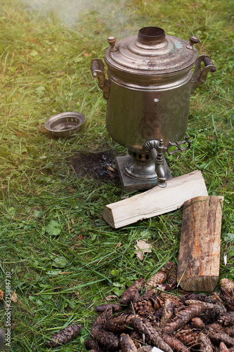 Heating the samovar with cones for making tea. The samovar stands on the grass.