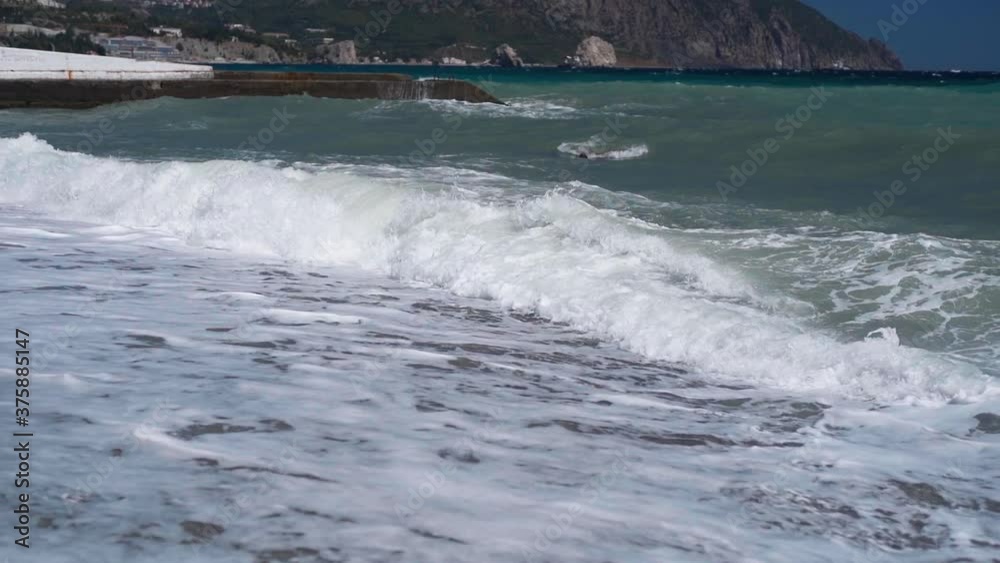 slow motion huge waves with white foam rolling on pebble sea beach. storm waves on public sea beach. waves are breaking on a breakwater slow motion huge waves with white foam rolling on pebble sea beach. storm waves on public sea beach. waves are breaking on a breakwater