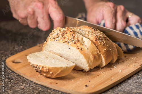 Homemade bread loaf being sliced with everything seasoning. Baking bread popular during pandemic.