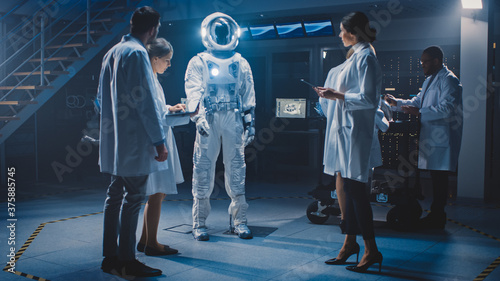 Diverse Team of Aerospace Engineers Design New Space Suit Adapted for Galaxy Exploration and Travel. Group of Scientists Wearing White Coats have Discussion, Use Computers. Constructing Astronaut Suit