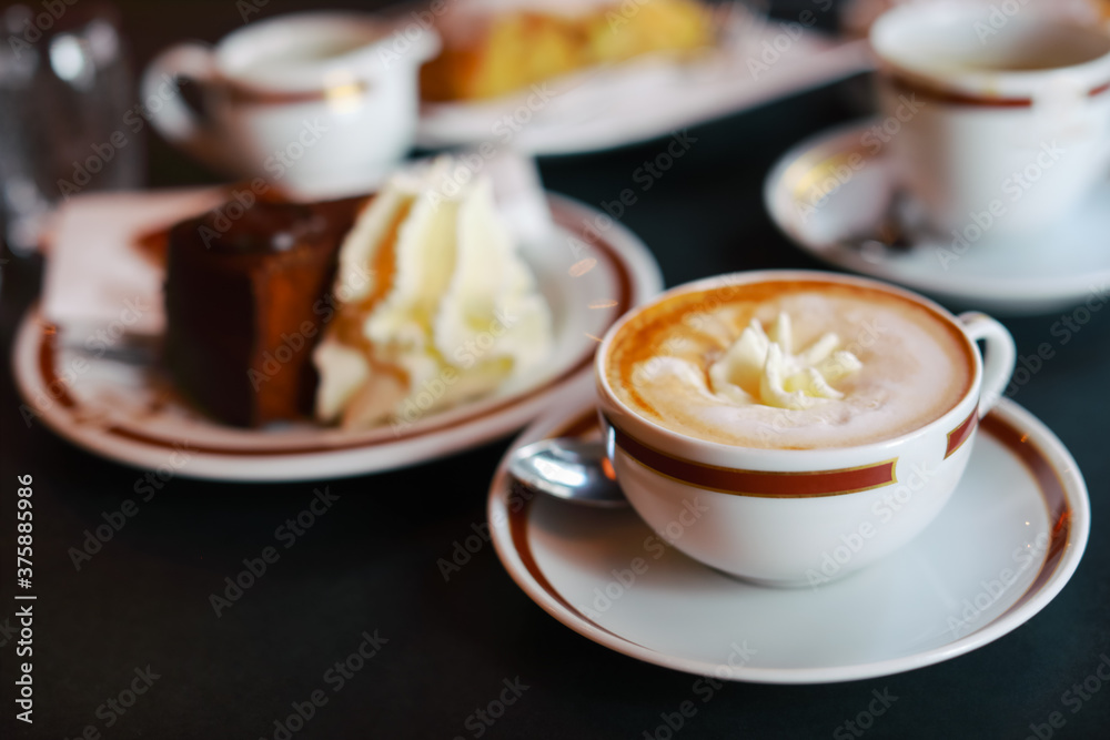 Coffee with cream in cap and with chocolate cake on table in cafe Coffee with cream in cap and with chocolate cake on table in cafe