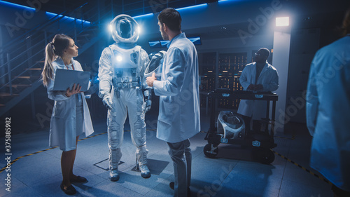 Team of Aerospace Scientists and Engineers Wearing White Coats have Discussion, Use Computers, Construct Astronaut Helmet for New Space Suit Adapted for Exploration and Travel.