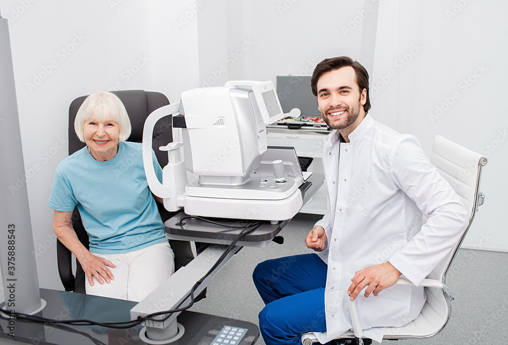 Smiling optometrist with his senior patient, friendly-looking at camera, eye check-up. Eye exam and vision diagnostic Smiling optometrist with his senior patient, friendly-looking at camera, eye check-up. Eye exam and vision diagnostic