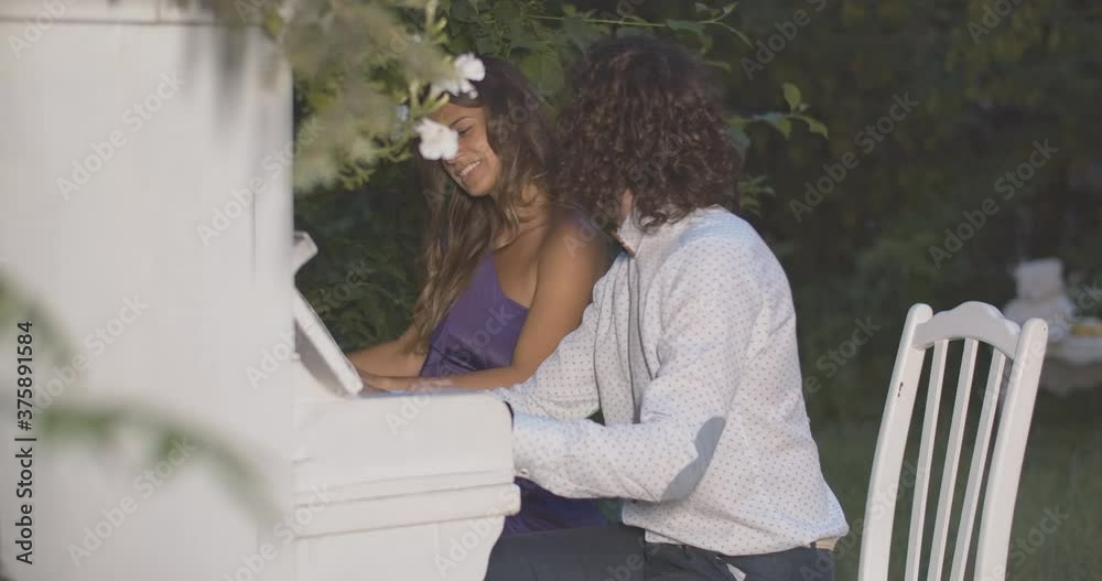 Side view of young passionate couple playing piano in evening garden. Portrait of elegant Caucasian male and female musicians performing at dusk. Cinema 4k ProRes HQ. Side view of young passionate couple playing piano in evening garden. Portrait of elegant Caucasian male and female musicians performing at dusk. Cinema 4k ProRes HQ.
