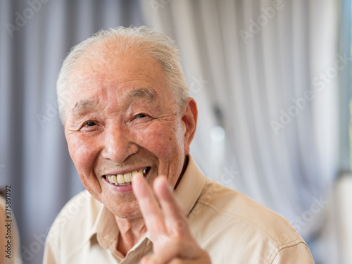 An elderly man smiling and showing a peace sign