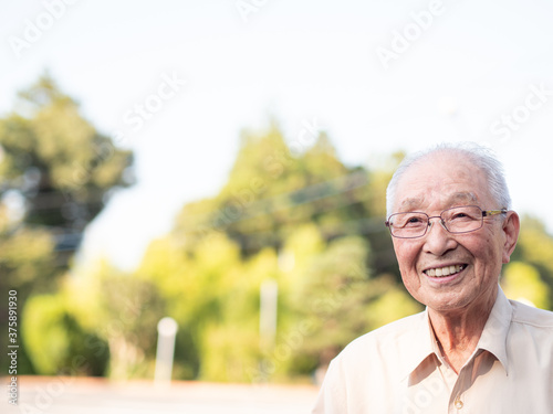 An elderly Asian man smiling happily outside