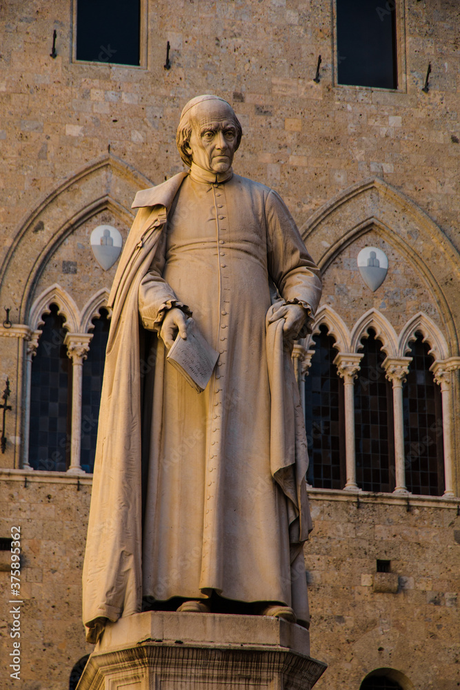Nice close-up view of the statue of Sallustio Bandini, local priest and economist, sculpted by Tito Sarrocchi in 1882, standing in the centre of the Piazza Salimbeni in front of the Palazzo Salimbeni.