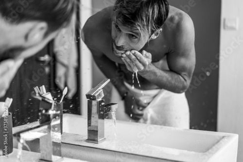 attractive man in the morning in the bathroom brushes his teeth washes his face, morning rituals.