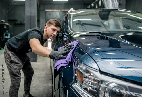 man holds the microfiber in hand and polishes the car