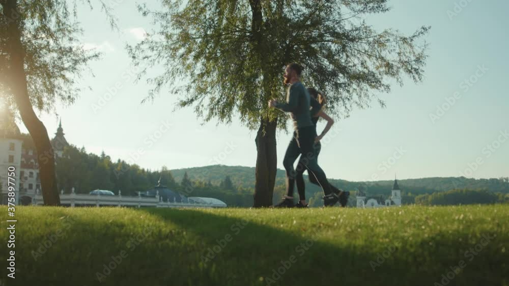 Man and woman running in park together jogging at outdoor workout at sunlight sportswear active young workout sport runner fitness cardio summer slow motion Man and woman running in park together jogging at outdoor workout at sunlight sportswear active young workout sport runner fitness cardio summer slow motion