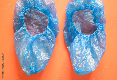 Medical blue cellophane shoe covers on a brown-orange background.